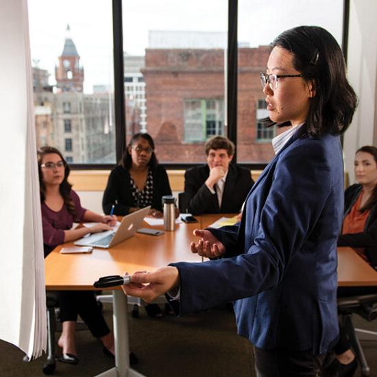 woman in professional attire speaking to college students